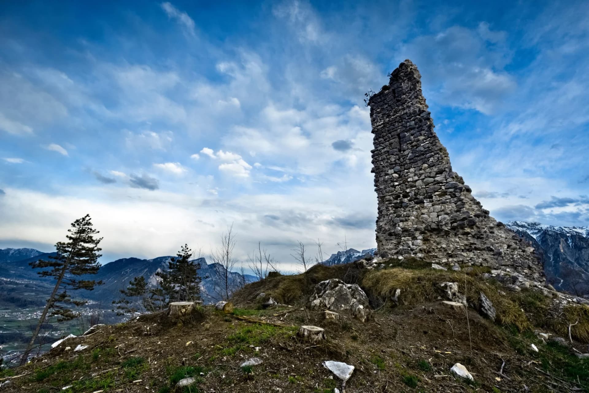 Medieval ruins of San Pietro Castle on Mount Ciolino overlooking valley and snow-capped mountains.