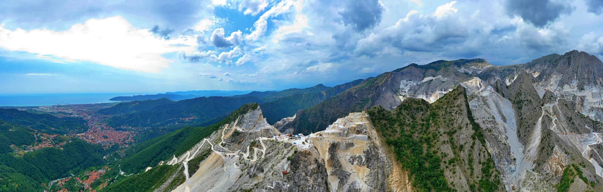 Aerial view of marble quarries in the Apuan Alps, Tuscany, overlooking the sea and a town.
