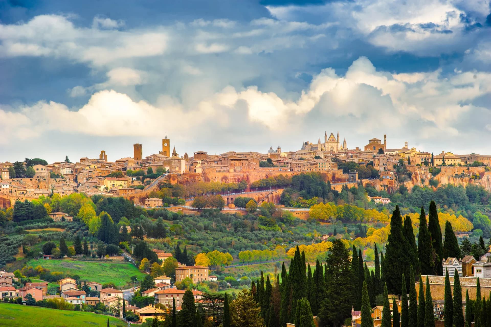 Panorama of Orvieto hilltop town with cathedral and clock tower under afternoon clouds.