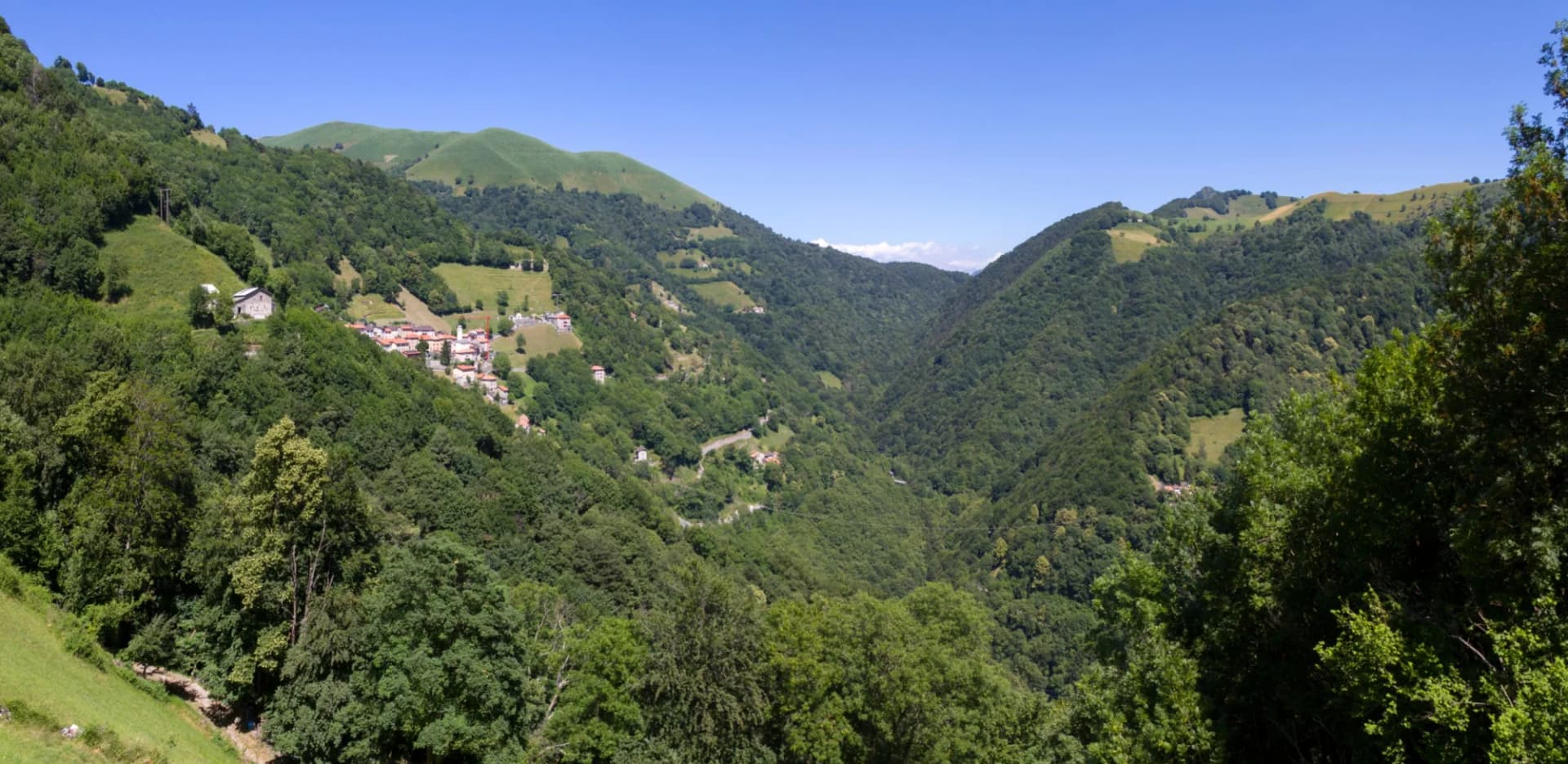 Mountain village nestled in lush green valley under clear blue sky