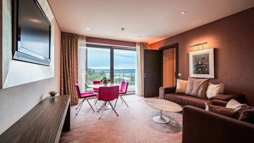 Hotel Kempinski Palace living area with balcony view of water and greenery