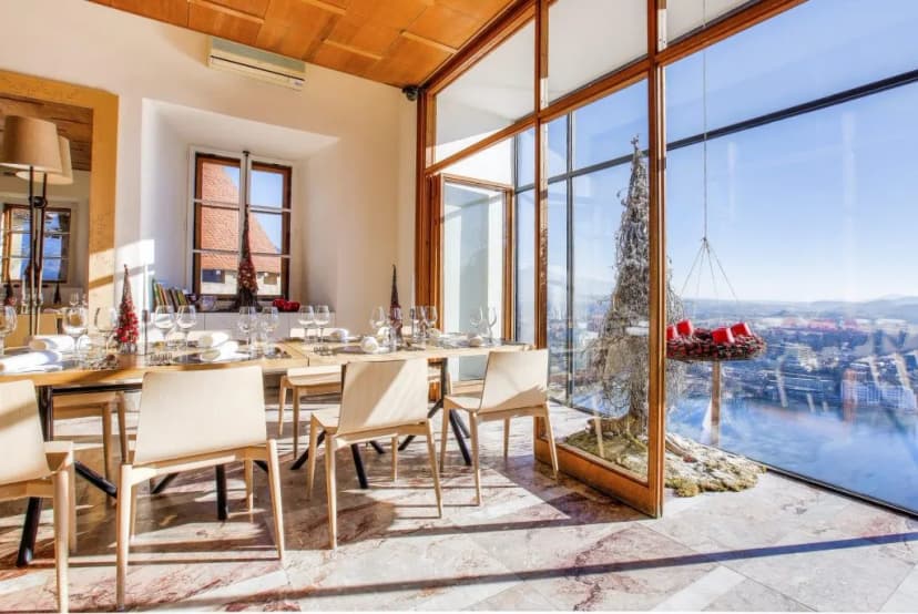 Dining room with set table and large windows overlooking a sunny city and water view.