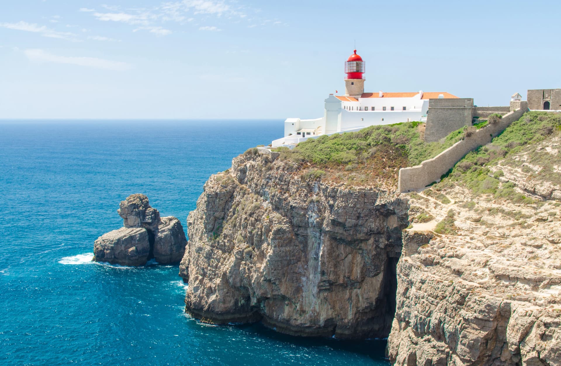 Portugal, Algarve, view of cliffs of Moher and Atlantic Ocean, white red lighthouse, lighthouse near Sagres in Portugal, Cape St. Vincent on a sunny day with The azure Atlantic in the background