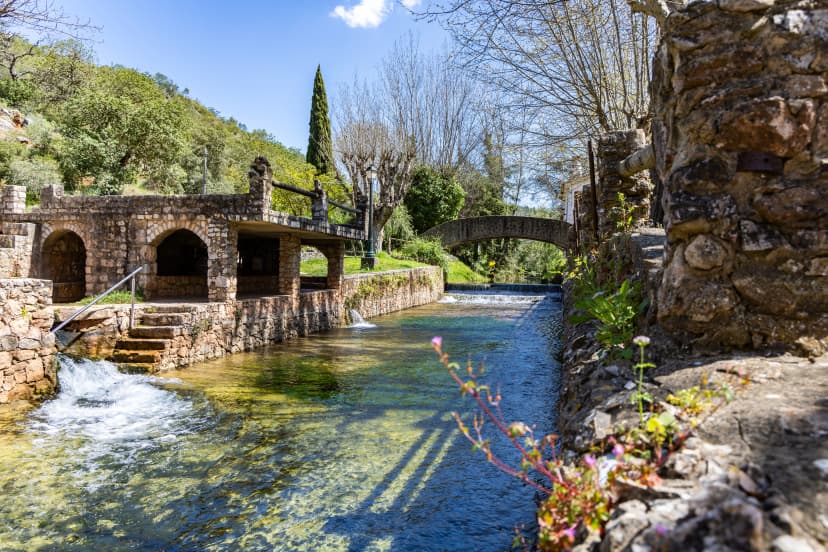 A fenced spring, a historic site that occasionally becomes a swimming pool. Old walls of the Praia Fluvial de Alte, in the Algarve, Portugal