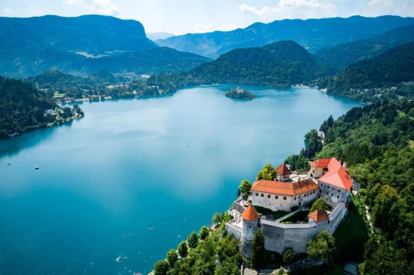 Lake Bled Castle overlooking turquoise lake and island, surrounded by forested mountains in Slovenia
