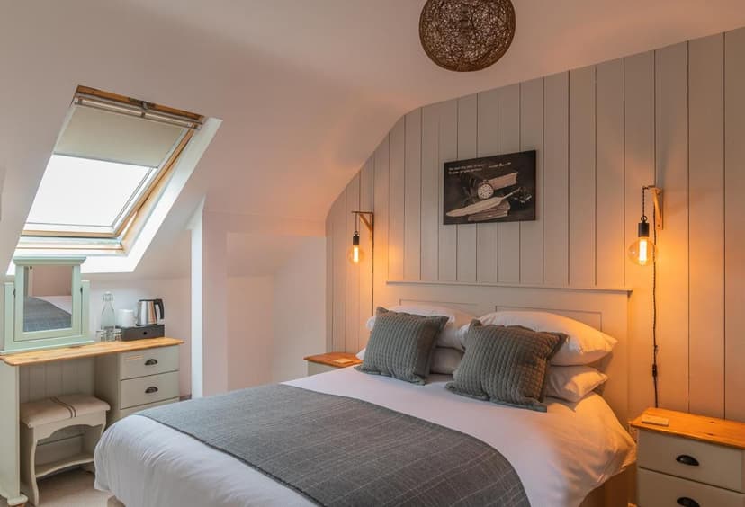 Attic bedroom with skylight, white bedding, grey pillows, and pendant lighting at Doolin View B&B