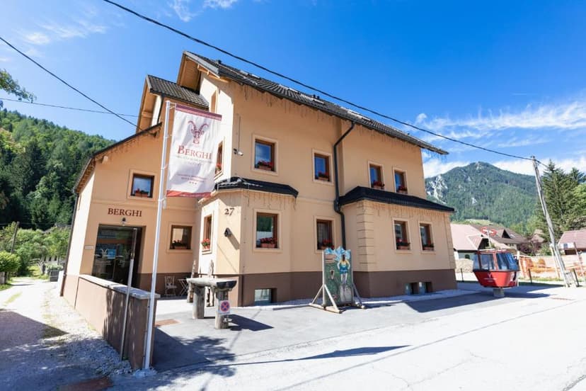 Berghi apartment building with banner, mountains, and red gondola cabin outside.