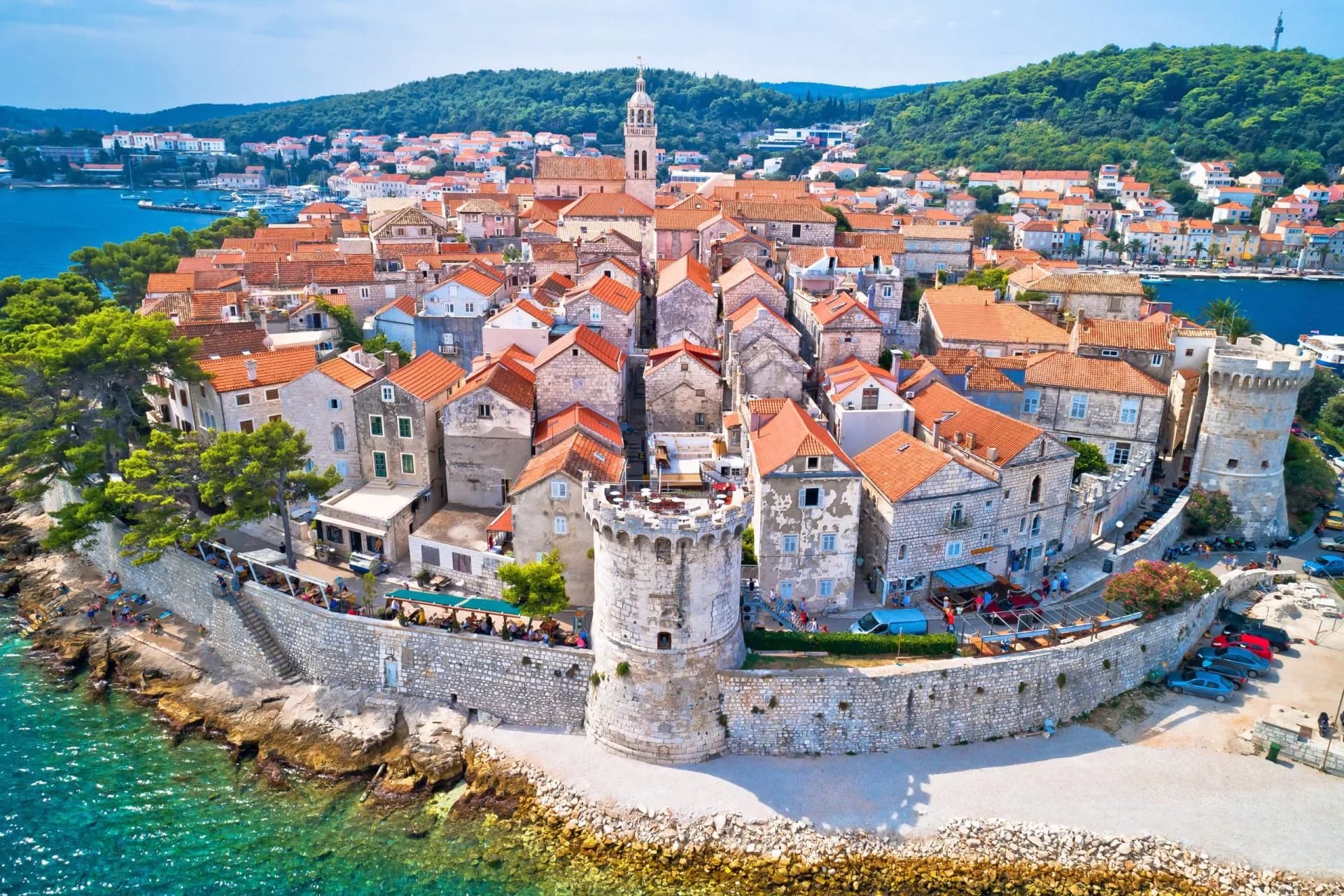 Korcula Old Town with stone walls, red-roofed buildings, and turquoise sea water.