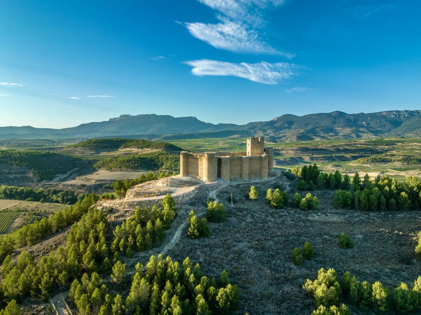 Aerial view of Davalillo castle above the Ebro river in Rioja Spain, with semicircular towers and tower of homage medieval defensive residential building, blue cloudy sky background