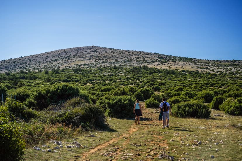 Back shot of two hikers walking in the hill top of the local mountain in island Krk, Croatia