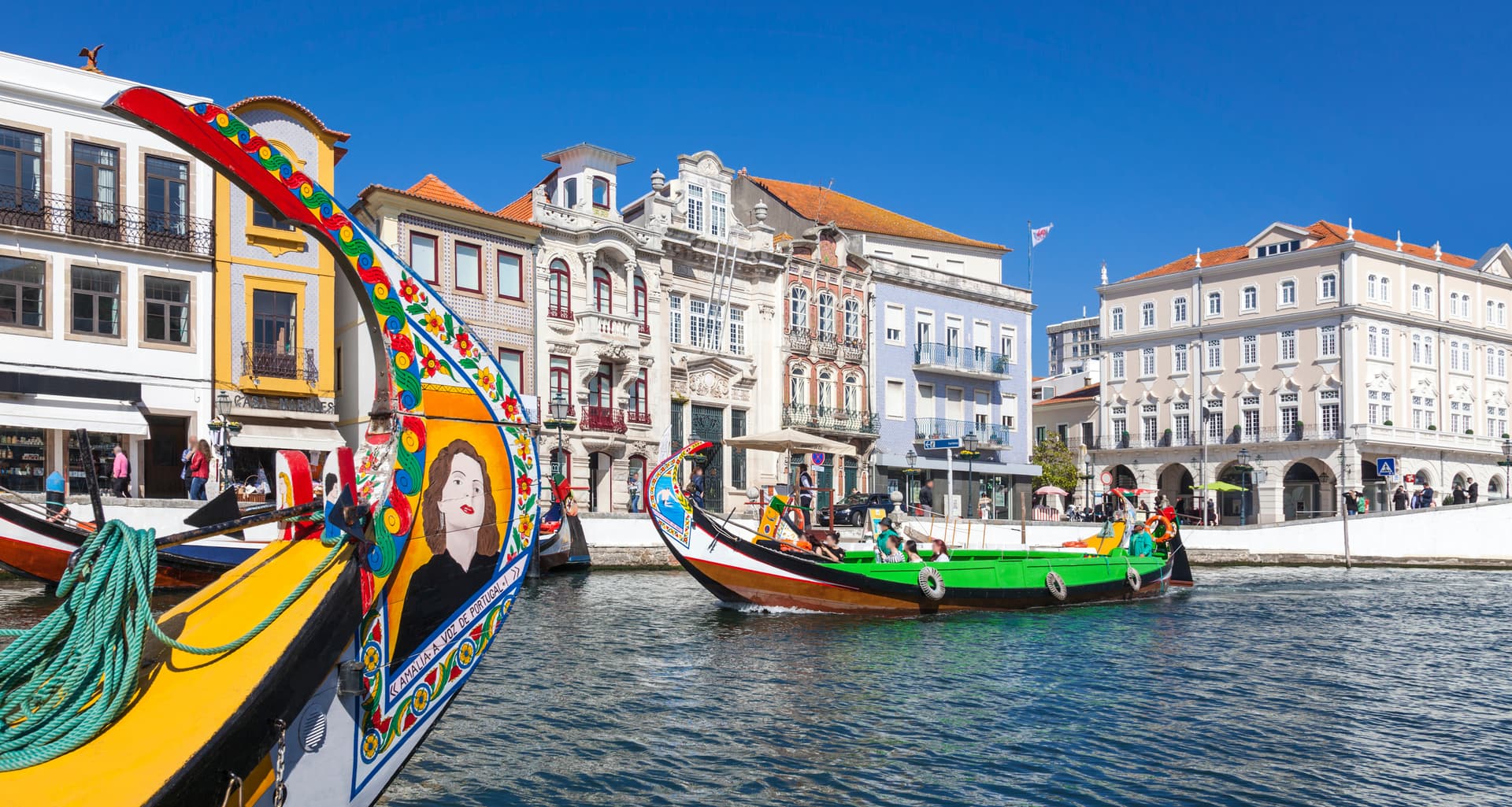 Colorful Moliceiro boats on canal with historic buildings in Aveiro, Portugal.