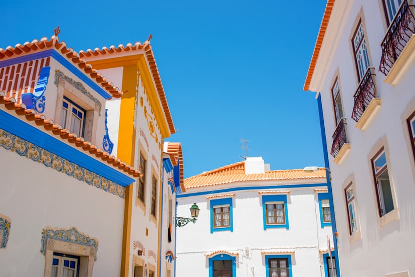White houses with blue trim and terracotta roofs under a clear blue sky in Ericeira.