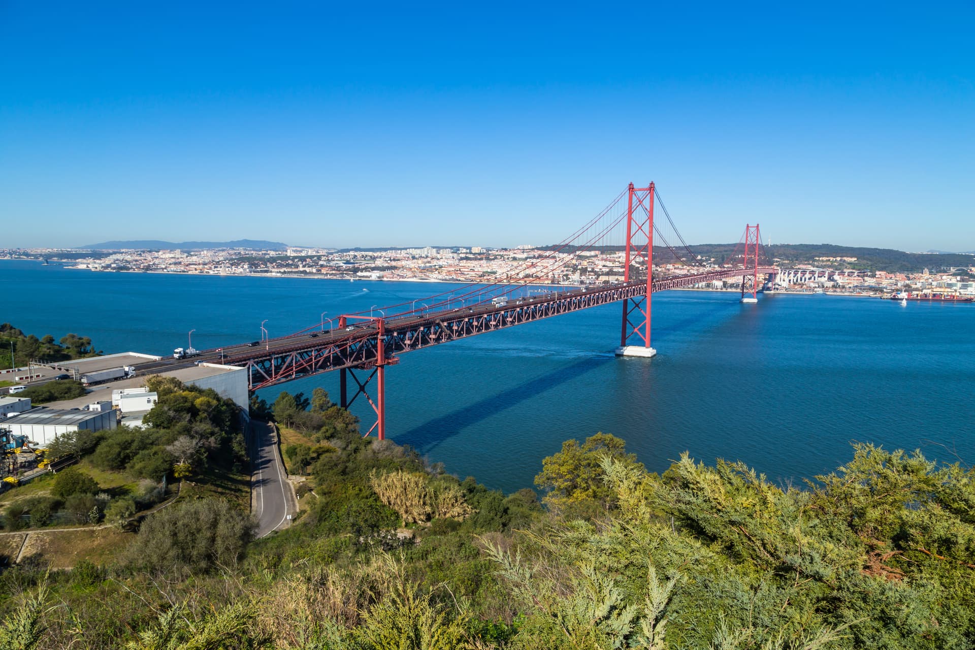 Ponte 25 de Abril bridge crossing blue water with Lisbon cityscape in the background