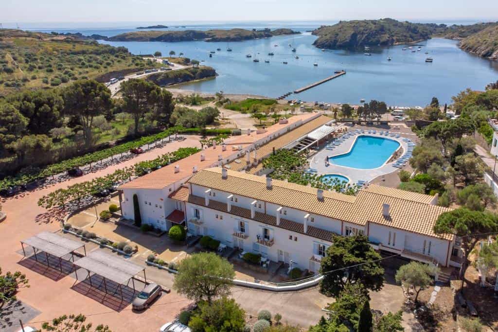 Resort with swimming pool overlooking a coastal bay with moored boats.
