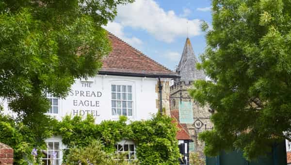 The Spread Eagle Hotel building with a stone church tower in the background.