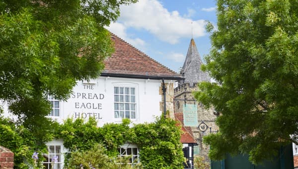 The Spread Eagle Hotel building with a stone church tower in the background.