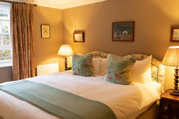 Cozy hotel bedroom with a double bed, floral pillows, and warm bedside lamps.