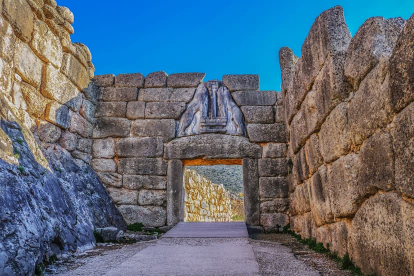 Bright Greek sunlight shines of rock wall of ancient Mycenae on the road up to the famous Lions Gate into the hill fortress where the armies of Troy originated