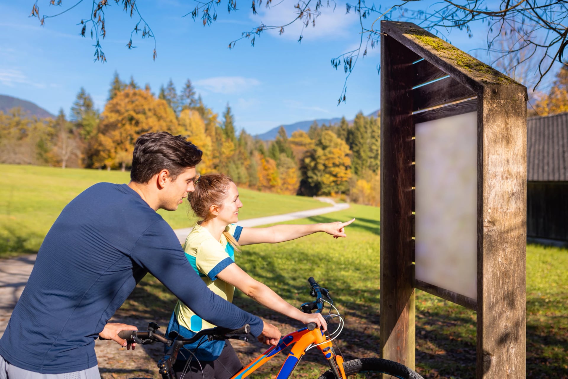 Cyclist woman and man looking at information board in nature