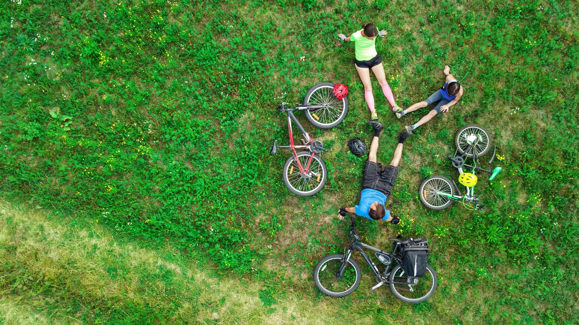Family cycling on bikes aerial view from above, happy active parents with child have fun and relax on grass, family sport and fitness on weekend