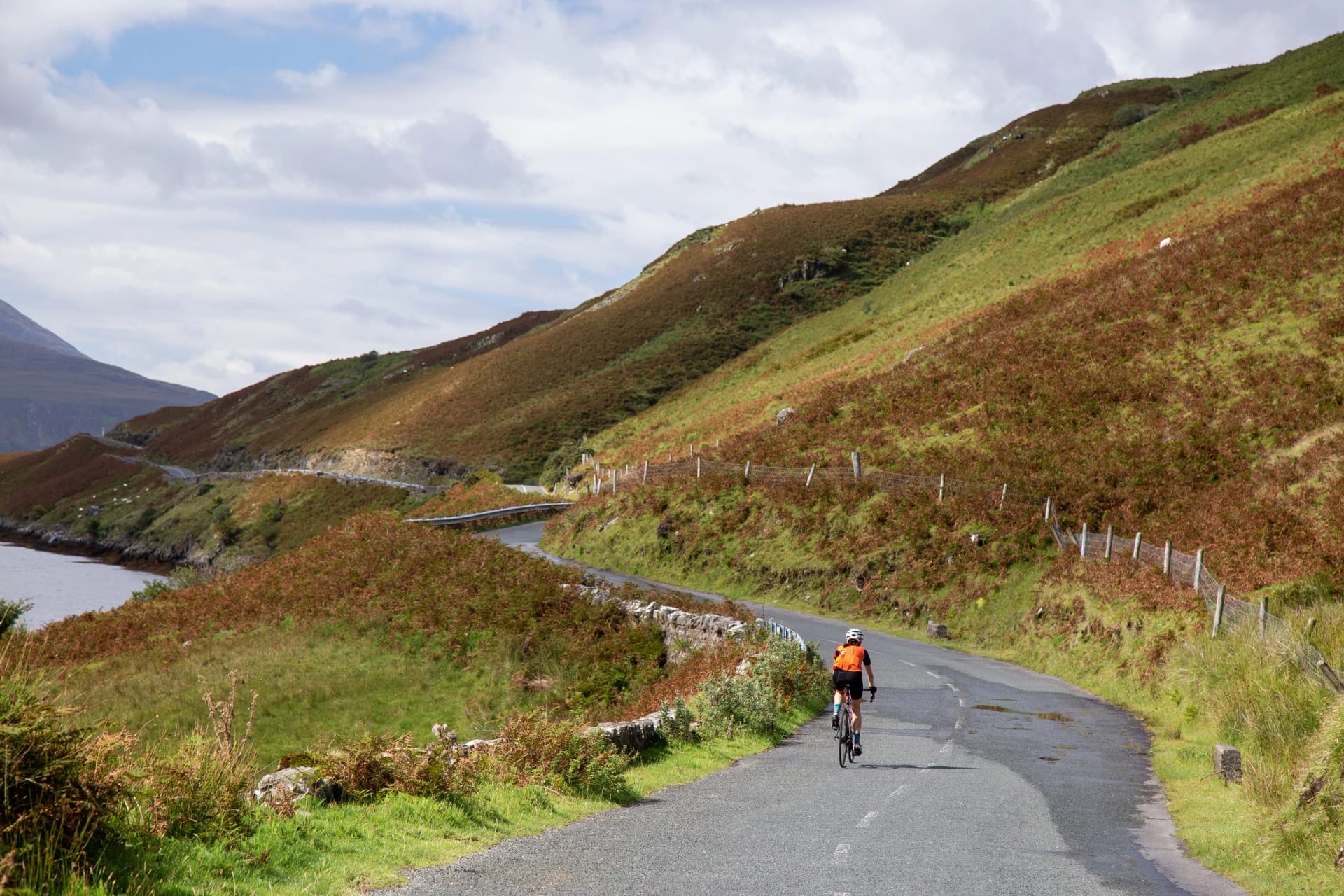 Cyclist on the R335 road along the shores of Killary Harbour, surrounded by hills and mountains, County Mayo, Ireland