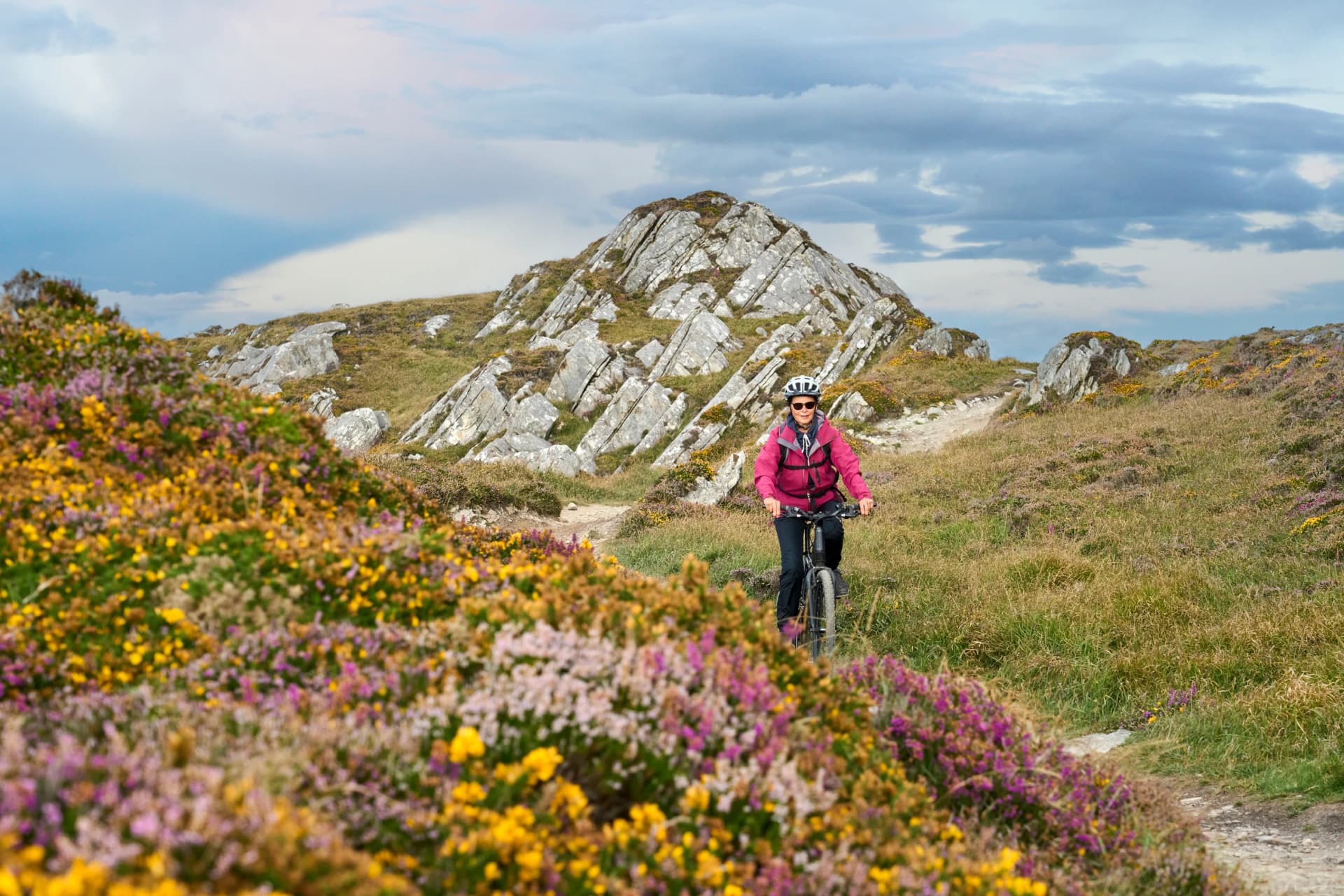 nice senior woman on mountain bike, cycling in sunset on the cliffs of Sheeps Head, County Cork, in the southnwestern part of the Republic of Ireland