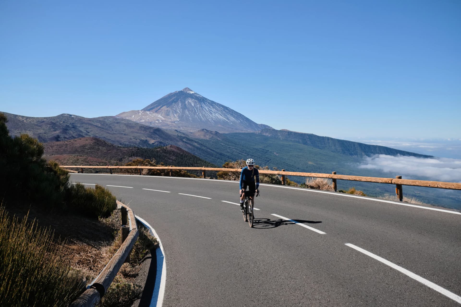 Cyclist on scenic mountain road with stunning volcano views. Perfect for travel, sports, and adventure themes. High-quality image ideal for various projects.