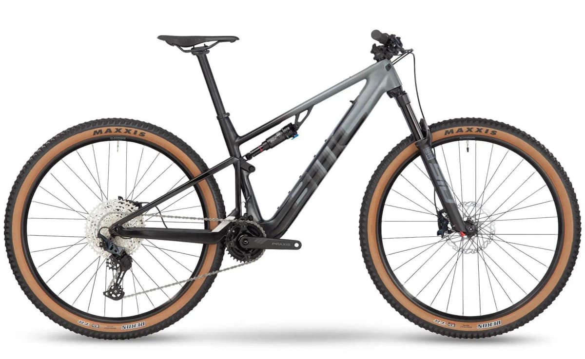 Grey full-suspension mountain e-bike with tan-wall tires on a white background.