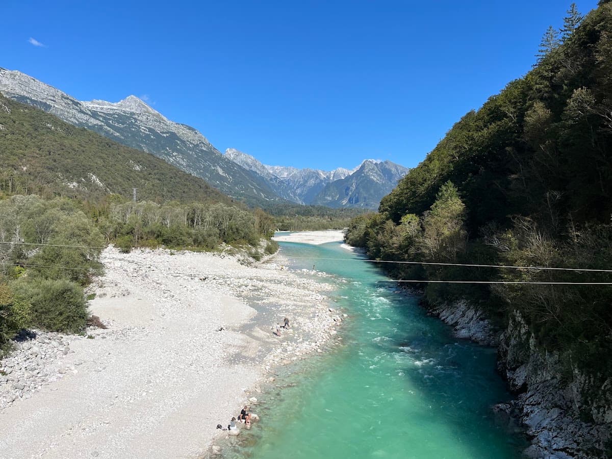Turquoise river flowing through a mountain valley with rocky shores and peaks under a clear blue sky