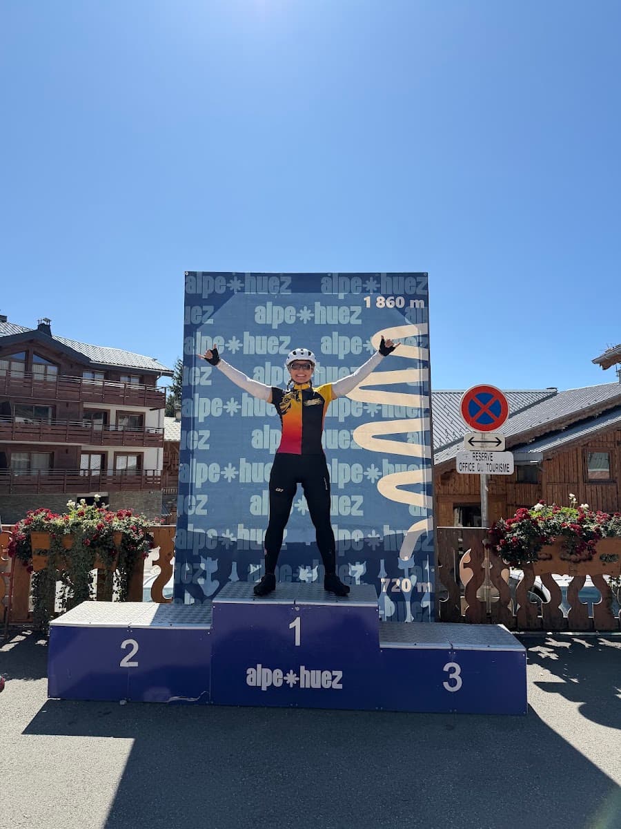 Cyclist standing on the first-place podium at Alpe d'Huez with arms raised